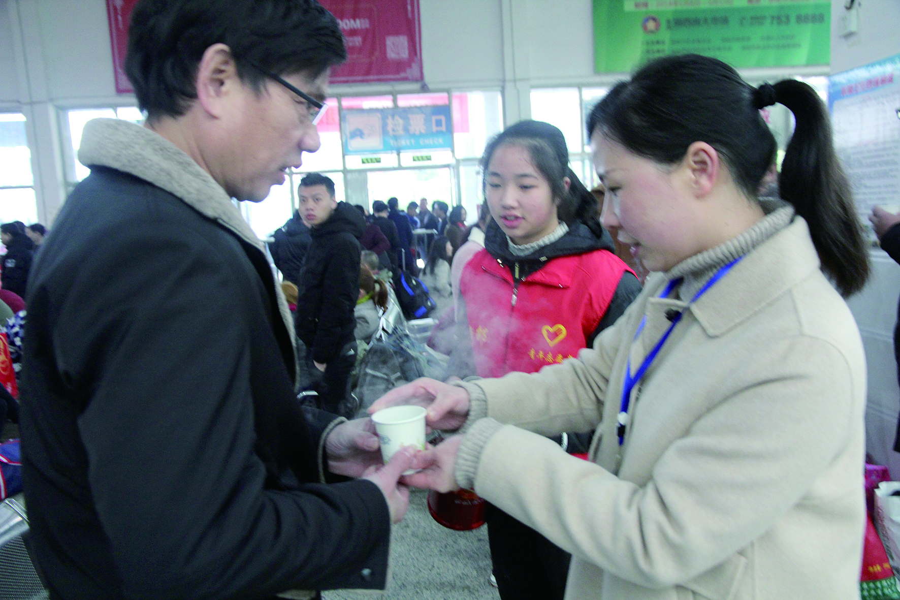 母女服務(wù)春運(yùn) 2月13日，記者在新邵分公司汽車站看到，該分公司安全科副科長李喜梅與其在新邵一中初中部1701班就讀女兒劉嘉怡在車站擔(dān)當(dāng)志愿者。李喜梅在候車室耐心為旅客釋疑解惑，劉嘉怡為旅客遞上一杯杯熱茶，有時(shí)母女也相互合作，其樂融融。 祖冠 攝影報(bào)道